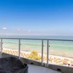 Terrasse mit Meerblick, Sonnenliegen und Strand im Hintergrund.