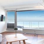 Wohnzimmer mit Meerblick, Holzboden, Sofa und TV an der Wand.