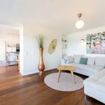 Wohnzimmer mit Sofa, Tisch und Wandbild. Holzboden und helle Wände.