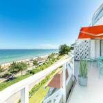 Terrasse mit Blick auf Strand und Meer. Liegestühle und orangefarbener Sonnenschutz.
