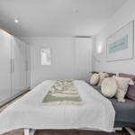 Schlafzimmer mit Bett, Kleiderschrank und Wandbild.