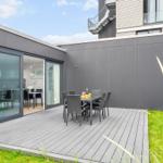 Terrasse mit Tisch und Stühlen, angrenzende Küche und modernes Gebäude.