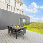 Terrasse mit Tisch und Stühlen, Blick auf Gras und Himmel.