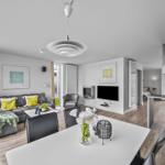 Wohn- und Essbereich mit Sofa, TV und Küchenzeile. Holzboden und modernes Design.