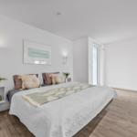 Schlafzimmer mit Bett, Wandbildern und Holzboden.