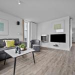 Wohnzimmer mit Sofa, Couchtisch und Fernseher. Holzboden und moderne Einrichtung.