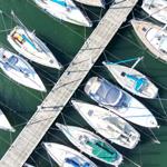Aerial view of boats docked at a wooden pier in calm water.