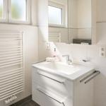 Badezimmer mit Waschbecken, Spiegelschrank und Heizkörper an der Wand.