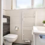 Badezimmer mit Toilette, Waschbecken und Heizkörper an der Wand.