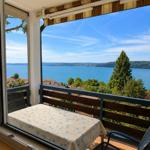 Balkon mit Tisch und Stühlen bietet Blick auf See und Landschaft.