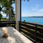 Tisch mit Kerze auf Balkon mit Blick auf See und Landschaft