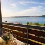 Balcony with table, wine glasses, and flowers overlooking a lake and hills.
