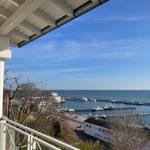 Blick von Balkon auf Hafen mit Booten und Meer unter blauem Himmel