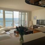 Wohnzimmer mit Meerblick, Sofa, Fernseher und Kücheninsel.