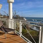 Terrasse mit Liegestuhl und Blick auf Hafen und Meer.