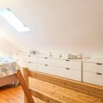Schlafzimmer mit Dachschräge, Bett, Schrank und Dachfenster.