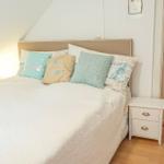 Schlafzimmer mit Bett, Kissen und Nachttisch. Holzboden und Dachschräge sichtbar.