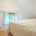 Schlafzimmer mit Bett, Fenster und Wanddekoration.