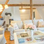 Wohnzimmer mit Sofa, Couchtisch und Holzbalken an der Decke.