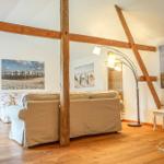Wohnzimmer mit Holzbalken, Sofa, Bodenheizung und Wandbildern