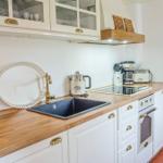 Küche mit Holz Arbeitsplatte, weißen Schränken und Edelstahl Spüle.