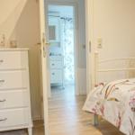 Schlafzimmer mit Bett und Schrank. Durchgang zur Badewanne.