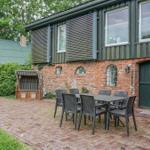 Haus mit Terrasse, Tisch und Stühlen, Beete und Gartenhaus im Hintergrund.