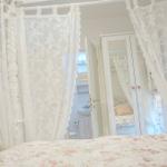 Schlafzimmer mit weißem Baldachin, floraler Bettdecke und Blick in Badezimmer.