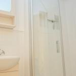 Badezimmer mit Dusche, Waschbecken und Spiegelschrank