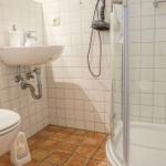 Badezimmer mit Toilette, Waschbecken und Dusche mit Glaswand.