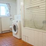 Badezimmer mit Badewanne, Dusche, Waschmaschine und Waschtisch.