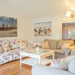Wohnzimmer mit drei Sofas, Glas-Tisch und Wandbildern an den Wänden.