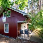 Rotes Holzhaus mit Terrasse und Garten in Waldnähe.