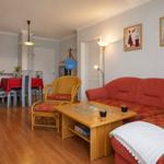 Wohnzimmer mit rotem Sofa, Holztisch und Essbereich im Hintergrund.