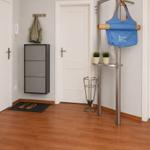 Eingangsbereich mit Kleiderhaken, Schuhschrank und Ständer mit Tasche.