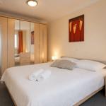 Schlafzimmer mit Doppelbett, Kleiderschrank und Nachttisch. Auf dem Bett liegen zwei Handtücher.