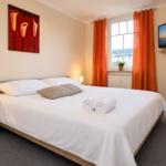 Schlafzimmer mit Bett, Fenster, TV und Wandbild.