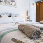 Double bed with patterned bedding and rolled towels. Background: wall art and wardrobe.