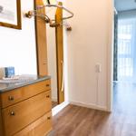 Closet with coat rack and dresser with candle and picture on the wall.