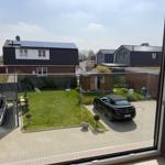 View from window showing paved courtyard, green lawn, and two parked cars.