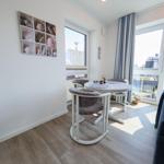Dining area with round table, three chairs, and window view. Wall art with shells.