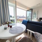 Round table with placemats and sofa in living area with view of the street.