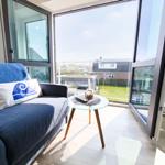 Living area with blue sofa, glass table, and view of a terrace.