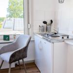 Küche mit Arbeitsfläche, Spüle und Kaffeemaschine. Fenster mit Blick auf Dächer.