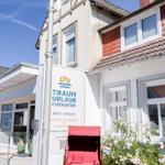 Ferienhaus mit rotem Schirm und Blumen vor einem weißen Gebäude.