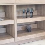 Holzregal mit Gläsern und Buddha-Statue auf den Regalen.