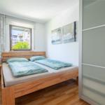 Schlafzimmer mit Holzbett, Fenster und Kleiderschrank.