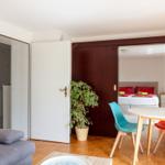 Wohnbereich mit Sofa, Esstisch und Blick in Schlafzimmer mit Bett.