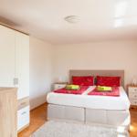 Schlafzimmer mit Bett, Nachttischen und Schrank. Auf dem Bett liegen Handtücher.