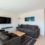 Wohnzimmer mit Sofa, Sessel, Couchtisch und Wandbild. Fernseher an der Wand.
